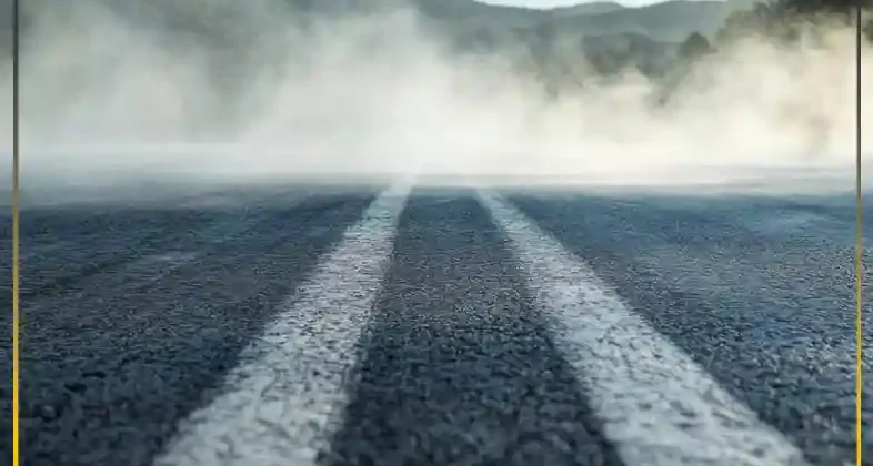 Steaming asphalt highway demonstrating high thermal resistance of premium bitumen under extreme summer heat conditions