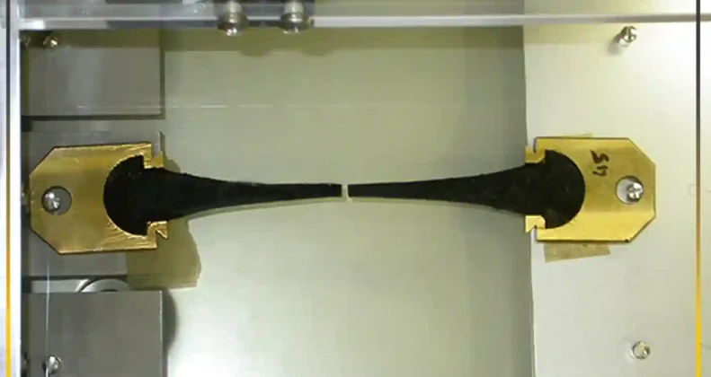 Standard laboratory ductility test of bitumen showing a stretched sample in a water bath to measure tensile strength and elongation properties